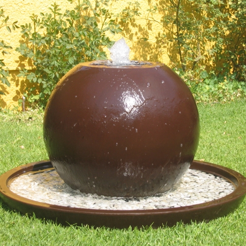 Fuente de esfera fabricada de fibra de vidrio en color café chocolate instalada en un jardin