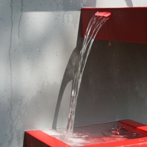 Chorro de agua cayendo de una charola a otra en la fuente de pared modelo Chilena