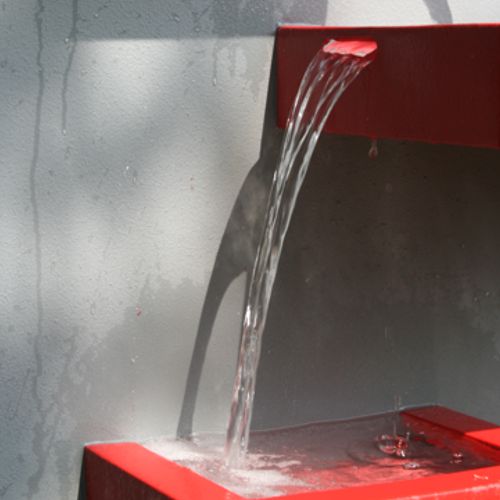 Chorro de agua cayendo de una charola a otra en la fuente de pared modelo Chilena