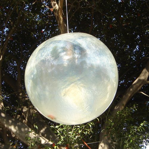 Esfera colgante de fibra de vidrio translucida o semi transparente colgada de un arbol