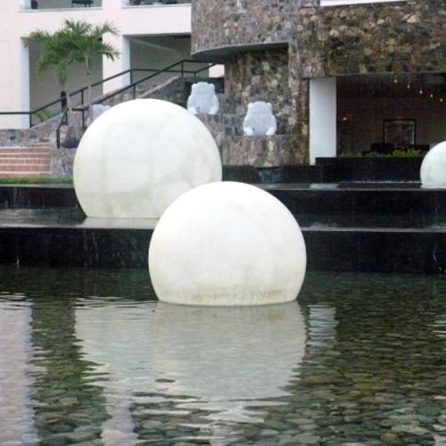 Esferas de fibra de vidrio iluminadas en un espejo de agua al exterior