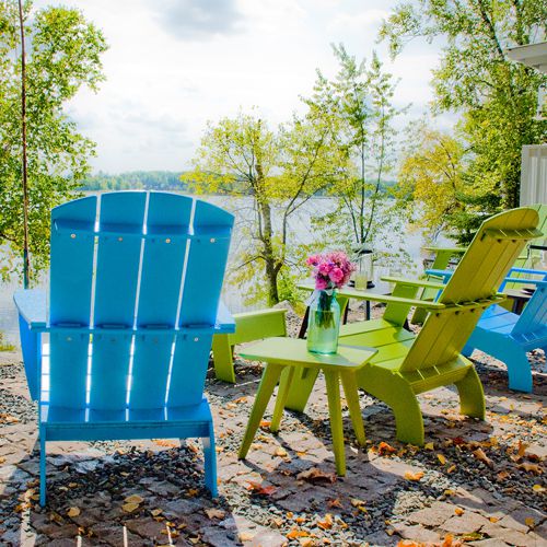 Sillon Adirondack de colores fabricado de plastico reciclado frente a un lago