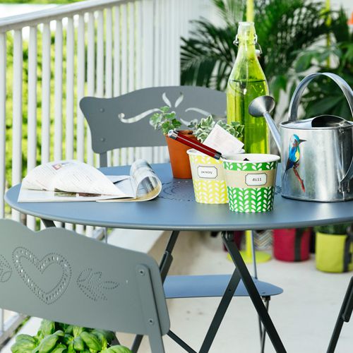 Detalle de una mesa en un balcon con sillas Bagatelle de Fermob