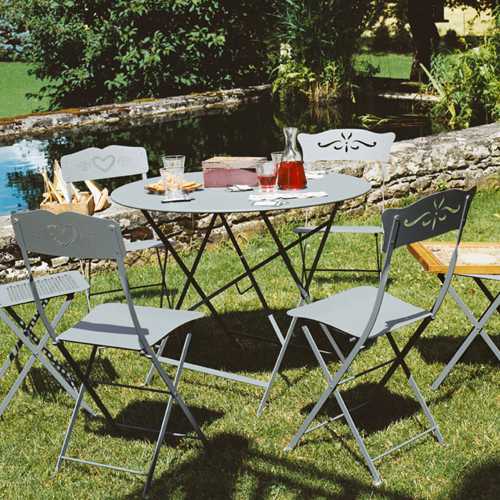 Mesa y sillas plegables modelo Bagatelle en colo gris en un jardin al exterior