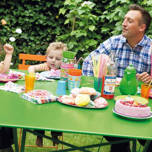 Detalle de la mesa Cargo de Fermob en color verde en un jardin con niños