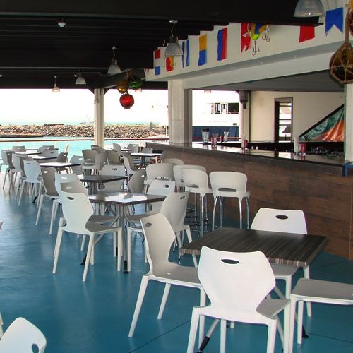 Restaurante con sillas Cielo en color blanco frente al mar
