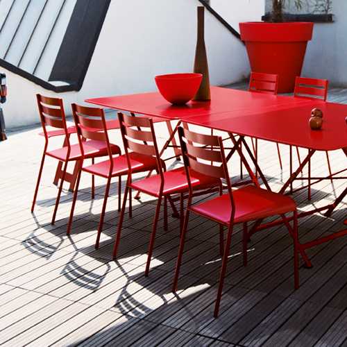 Comedor en una terraza con sillas Facto de color rojo resistiendo la intemperie