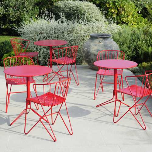 Juego de mesitas y sillas modelo Flower Fermob al exterior de un restaurante color rojo