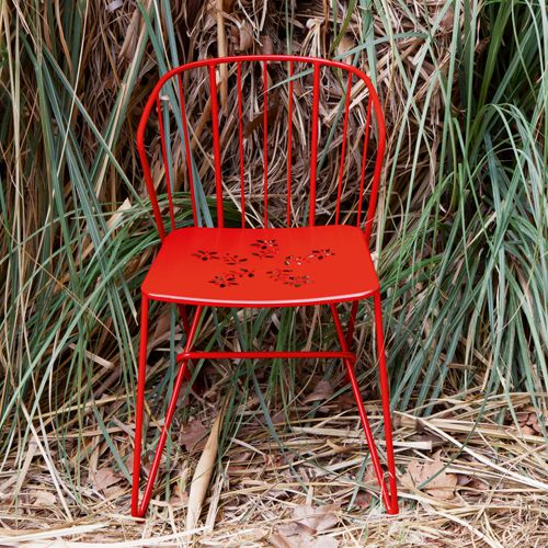 Silla Flower para jardin en color rojo con un diseño exquisito enfrente de plantas