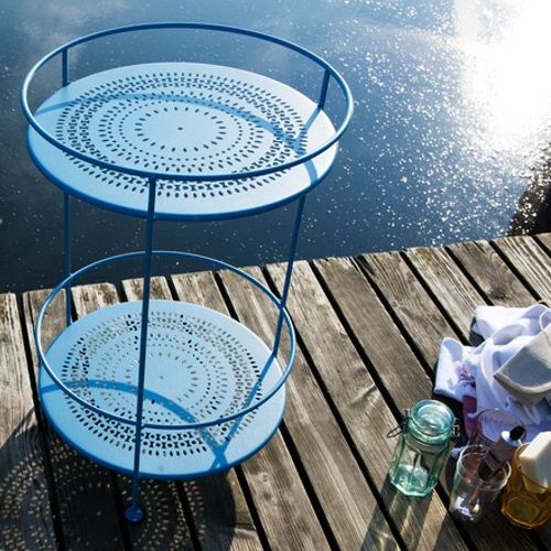 Mesita de apoyo redonda o lateral llamada Gueridon de Fermob frente al mar o lago