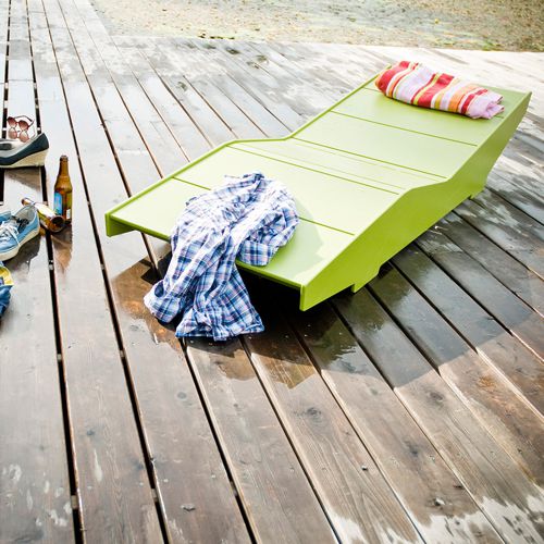 Camastro o asoleadero Luge de Loll Designs moderno de color verde y de plastico reciclado en una terraza o deck frente al mar