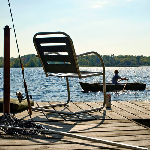 Silla Pliny para exterior frente a un lago con un bote al aire libre fabricado por Loll Designs ideal para un dia de pesca