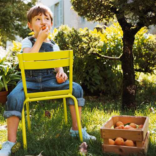 Niño y su silla Luxembourg Kids color Verbena fabricada en Francia por Fermob de aluminio