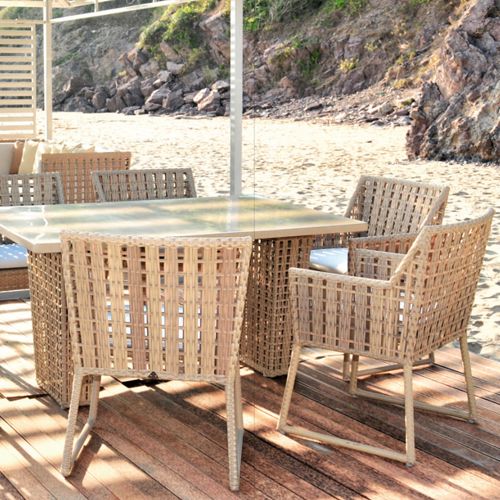 Comedor de exterior Meleta en una playa con mesa rectangular y varias sillas en un deck sobre la arena de alta calidad
