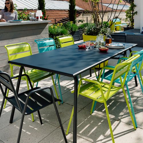 Mesa y sillas en un comedor Monceau de Fermob en una terraza al exterior con colores atrevidos y vivos