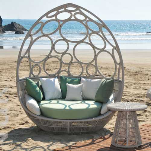 Sillon Nuk en forma de huevo con cojines de tela Sunbrella en la playa frente al mar