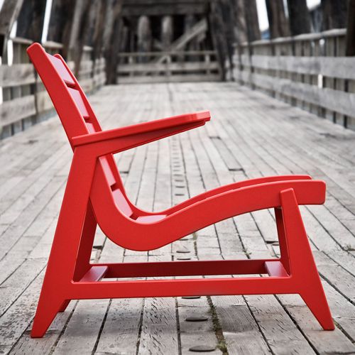 Perfil del alto diseño de la silla Rapson de Loll Deisgns en color rojo en una terraza o deck al exterior fabricado de botes de leche reciclados
