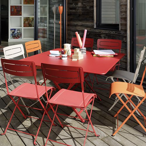 Sillas Slim de colores rodeando una mesa plegable cuadrada en una terraza