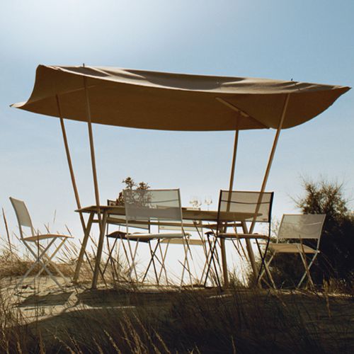 Comedor de exterior en la playa arena con la famosa mesa Tablabri de Delo Lindo para Fermob