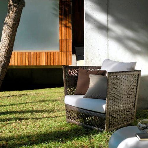 Sillon Tunis de aluminio y polirattan Viro al exterior en un jardin bajo la sombra de un arbol