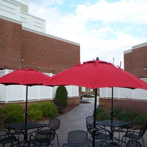 Sombrillas rojas redondas de fibra de vidrio de la colección Daytona en un restaurante o cafeteria